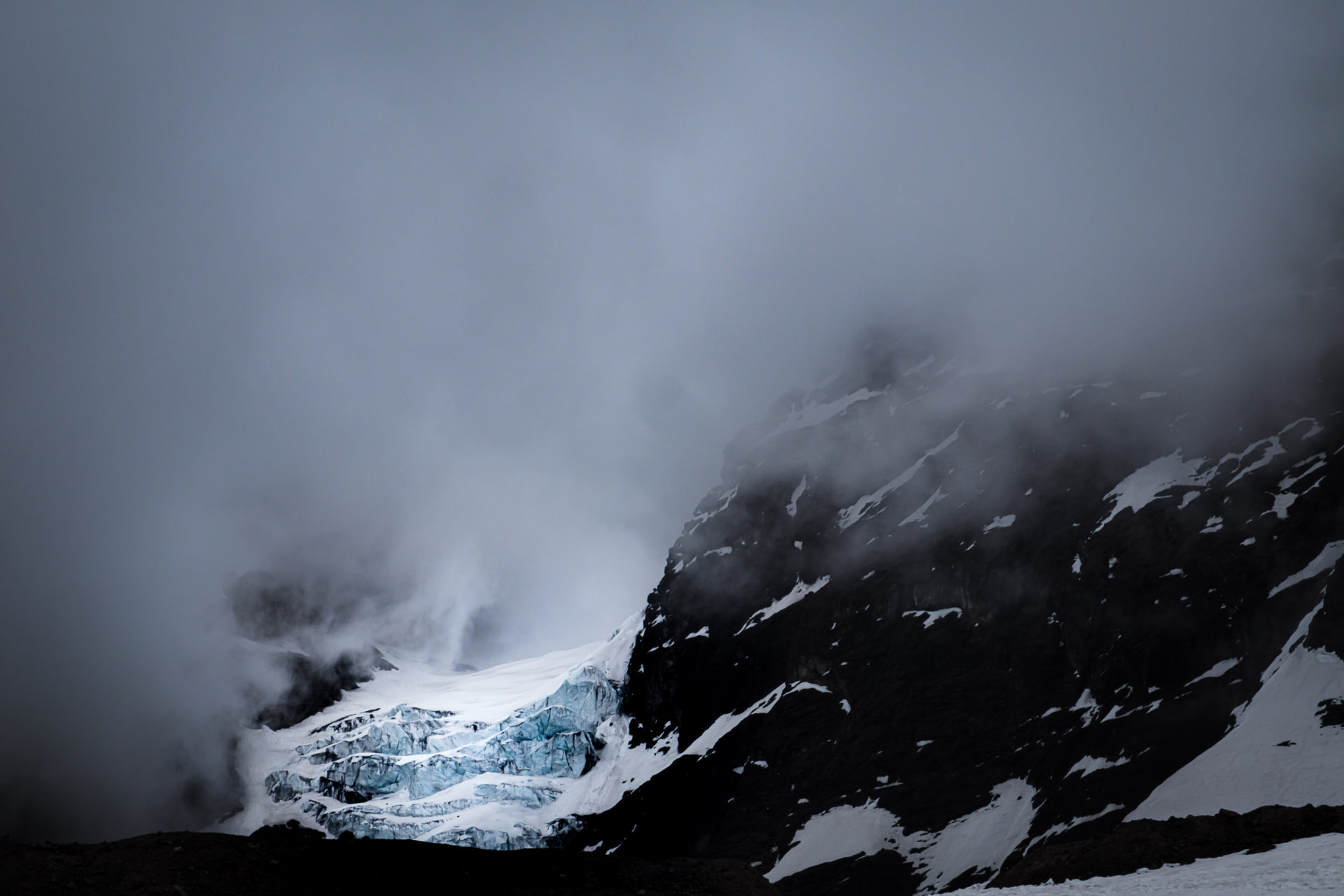 Glaciar colgante El Morado de tono azul rodeado por una nube, en un paisaje invernal