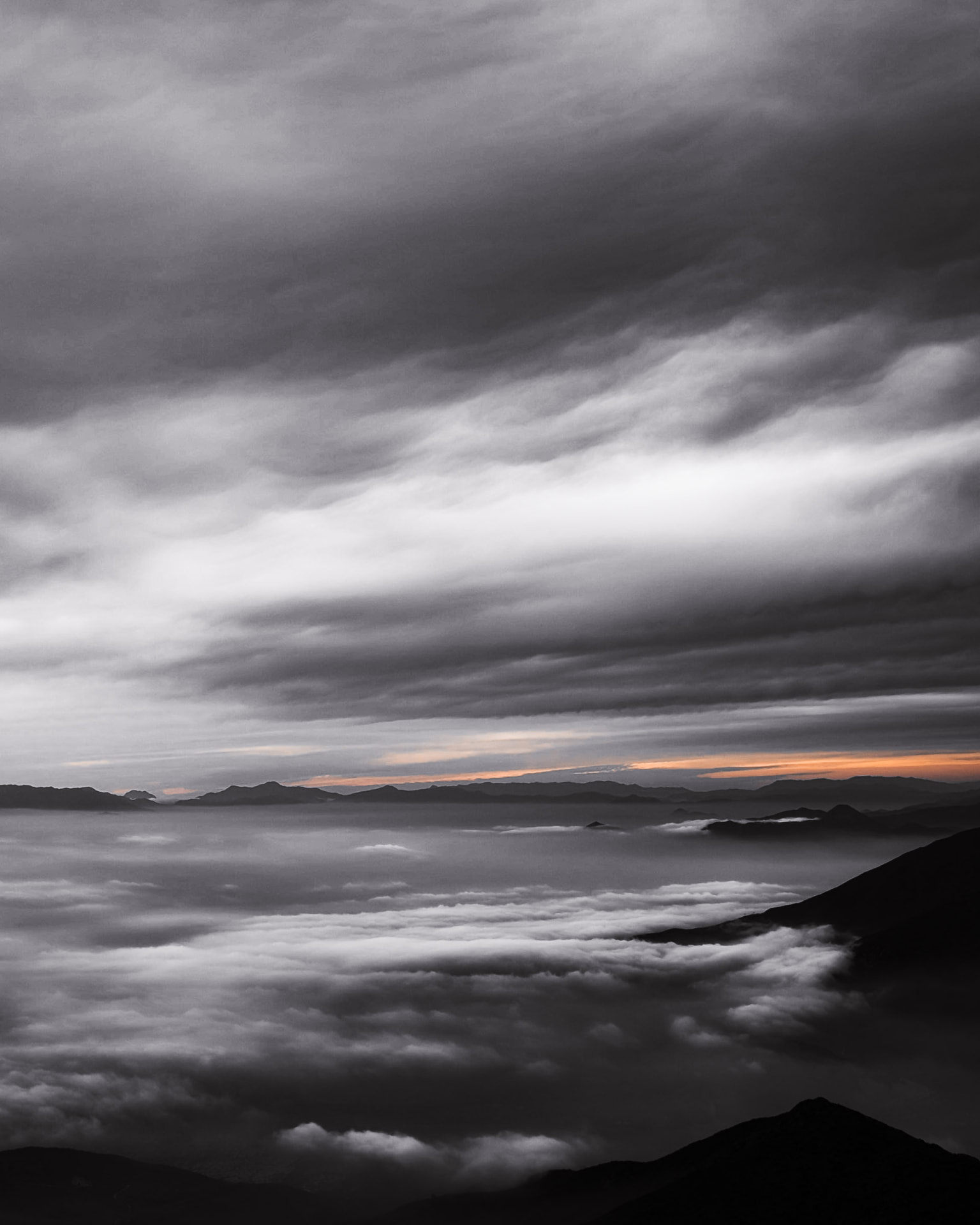 Valle de Santiago cubierto por nubes visto desde el Cerro Papagayo, con una franja naranja en el horizonte