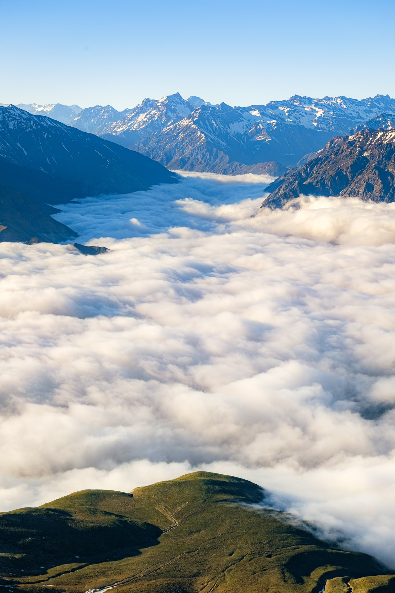 Valle del Cajón del Maipo cubierto de nubes con carpas de montañistas en el plateau del Cerro San Gabriel