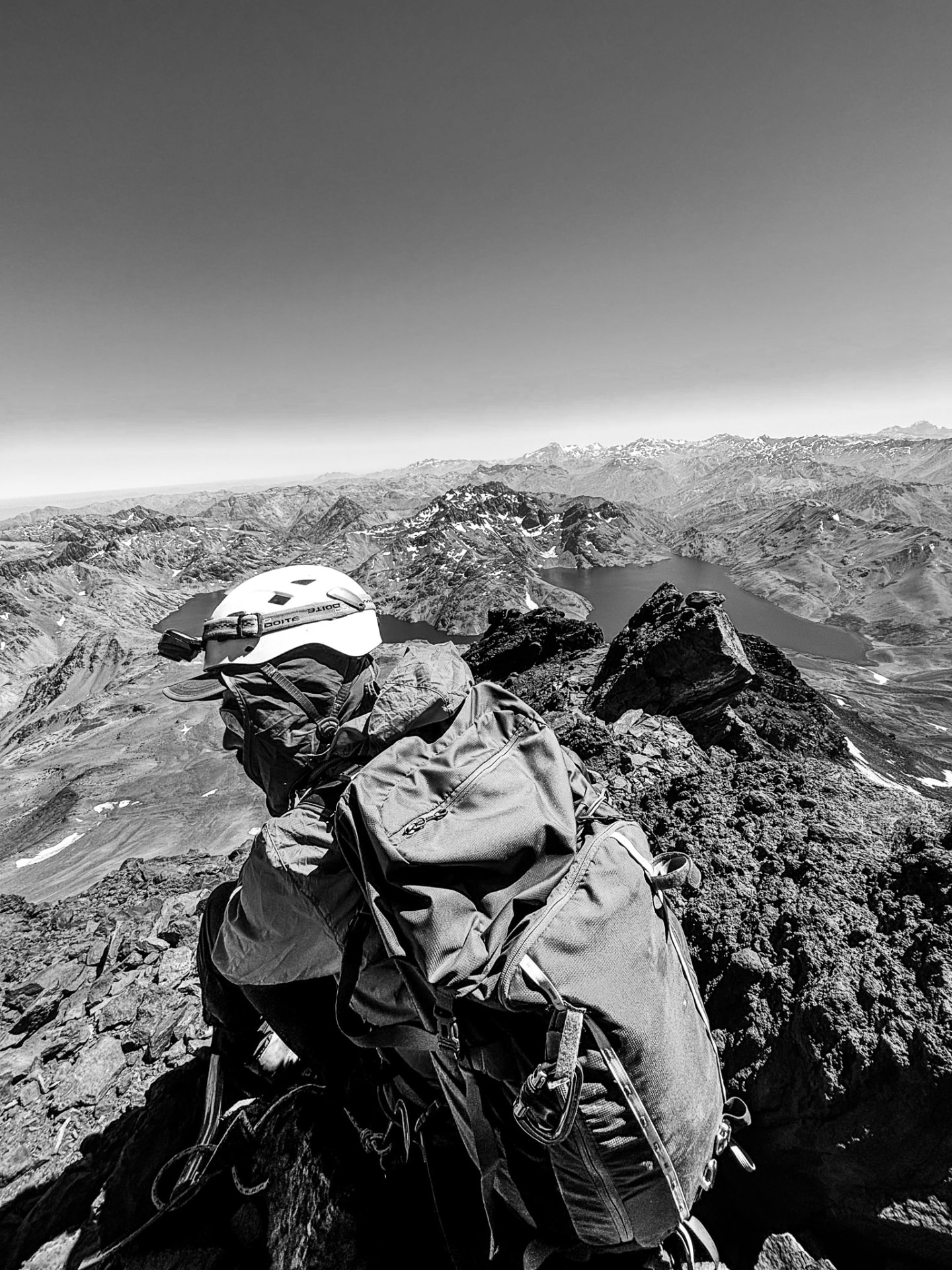 Montañista en la cumbre del Planchón, con la cordillera y la laguna al fondo