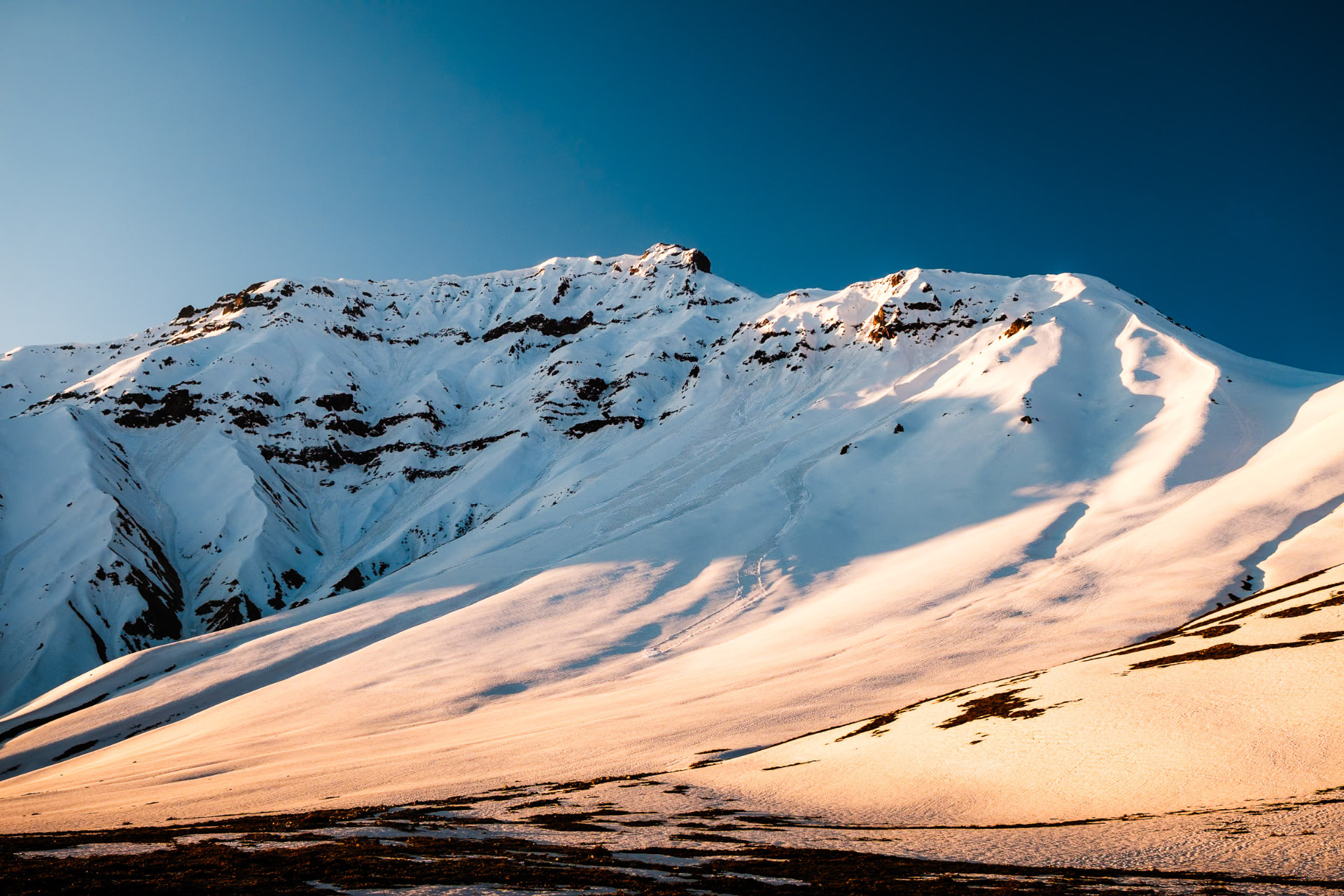 Arista nevada del Cerro San Gabriel iluminada por una luz dorada bajo el cielo azul
